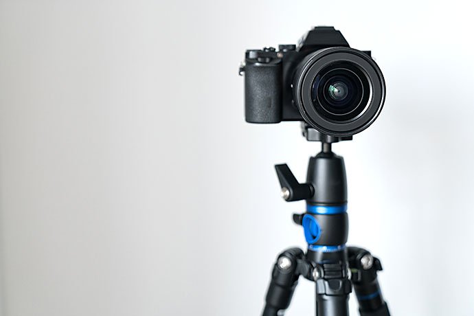 professional-black-mirrorless-camera-stands-on-a-tripod-against-a-white-wall-blogging-and-video-photo-shooting