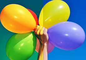 An image of a person's hand holding colorful balloons. The colors in half of the image have been adjusted.
