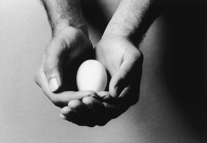 Foto blanco y negro en primer plano de dos manos sosteniendo un huevo