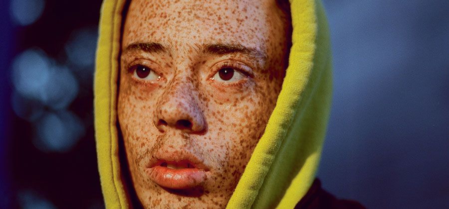 Portrait photo of woman with freckles on black background