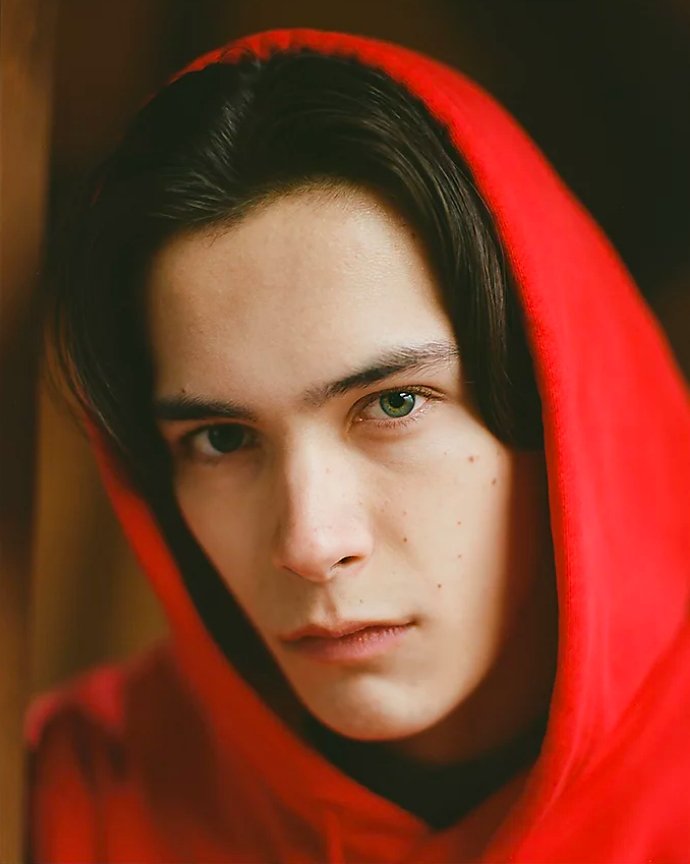 Portrait image of a young man in a red hoodie.