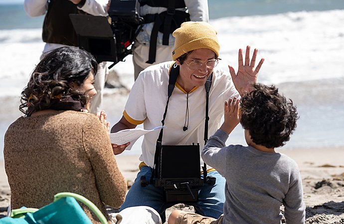 Un regista che dà il cinque a un bambino sul set di una spiaggia per una produzione di video