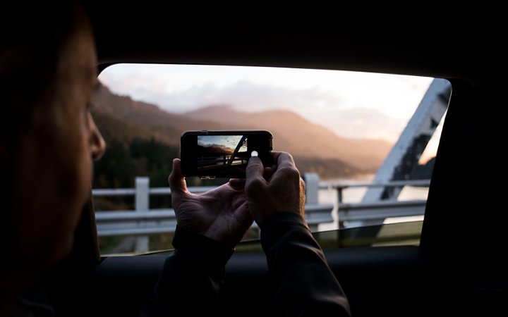 A photo of a person taking a photo with a smartphone from inside a car.