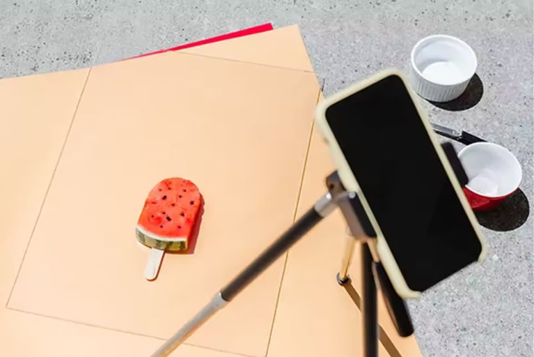 Ein Handy auf einem Stativ, das für eine Stop-Motion-Animation ein Stück Melone abfotografiert.