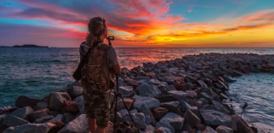 Фотограф, снимающий закат с залива на пляже
