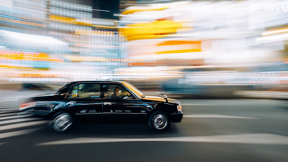 거리를 달리는 검은 택시 사진에 나타난 빛줄기와 모션 흐림