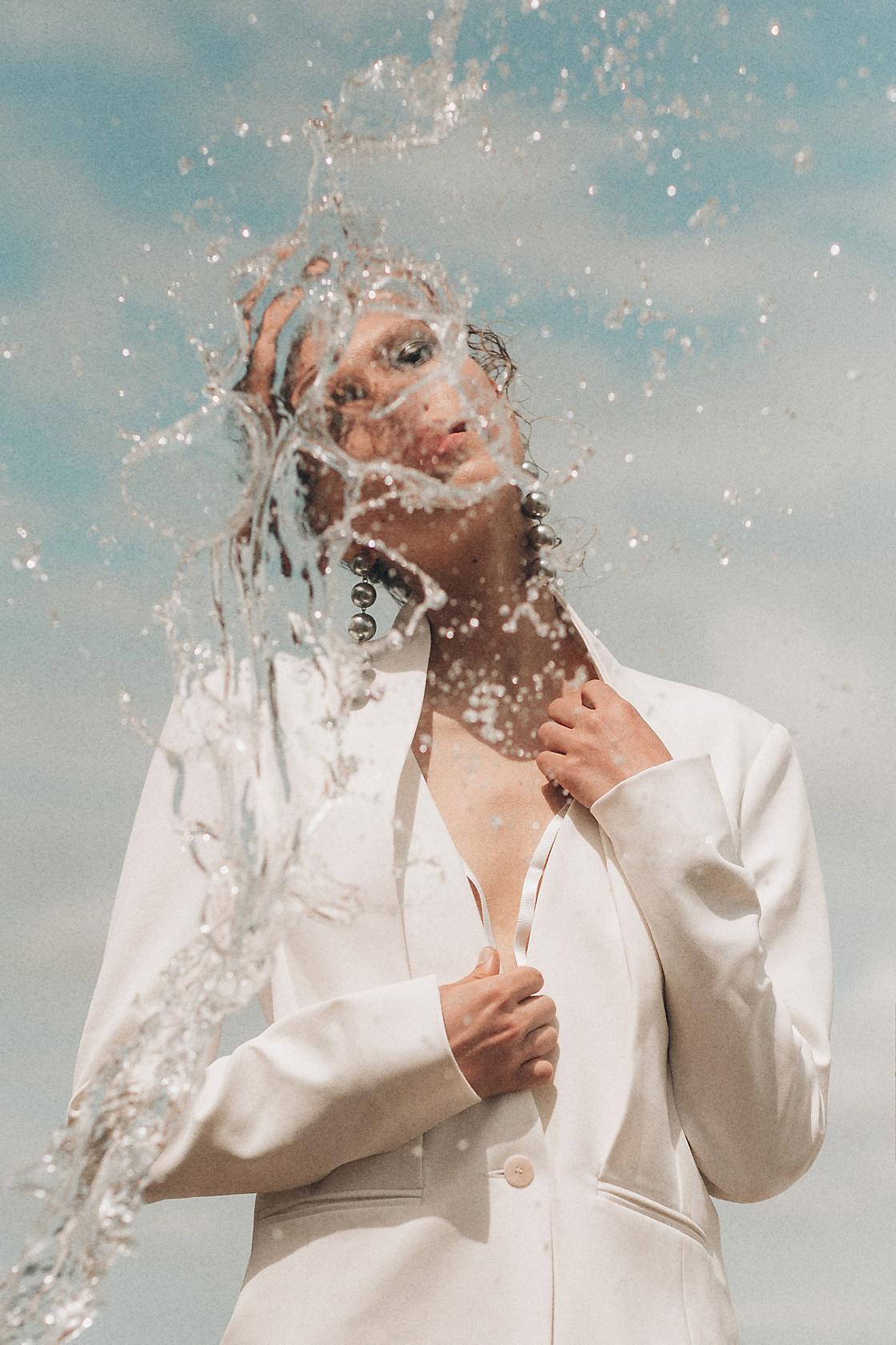 Editorial fashion photo of model being splashed with water
