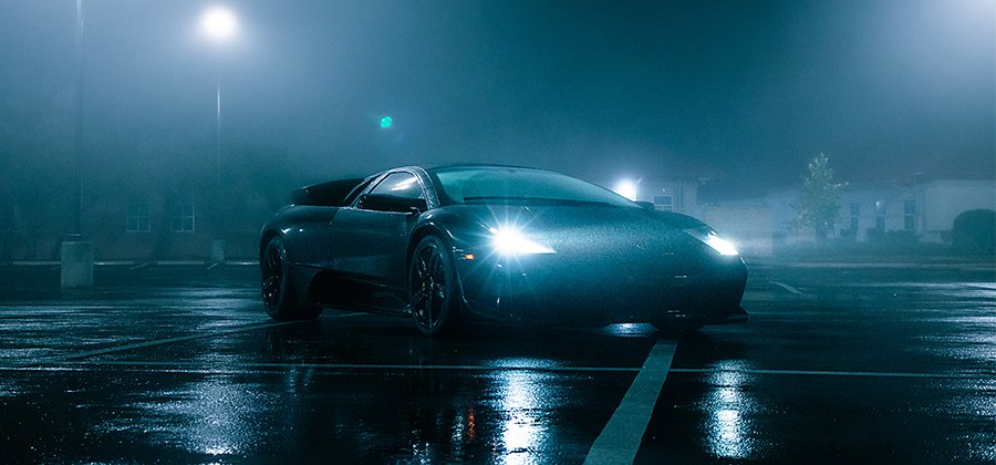 A nighttime photo of a sports car with raindrops on it