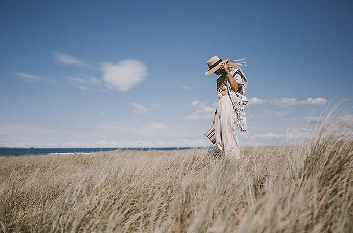 Woman at the beach in summer linen clothing on a windy day.