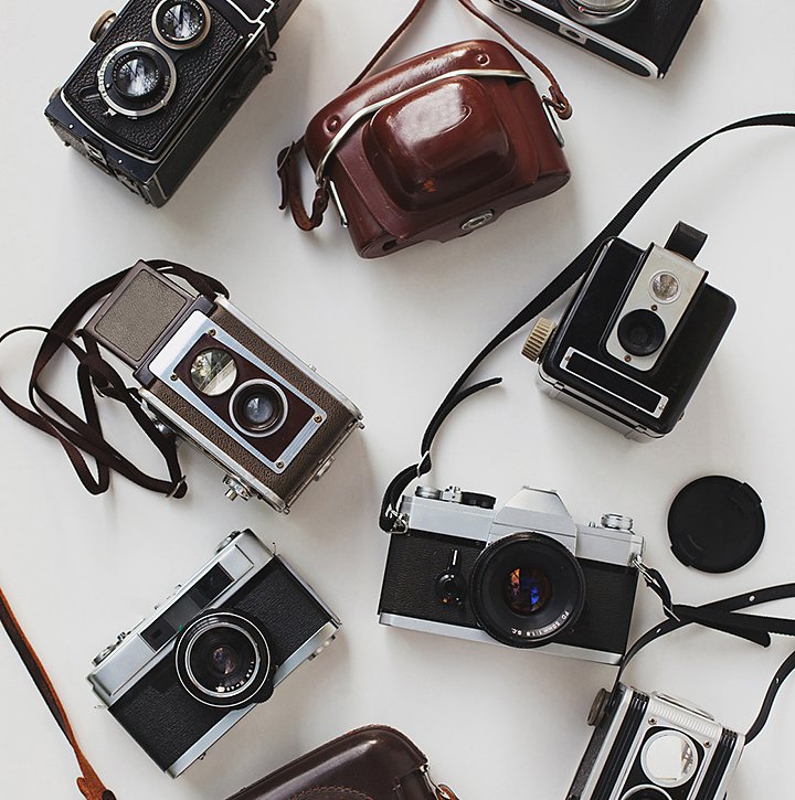 A variety of film cameras spread out on a table