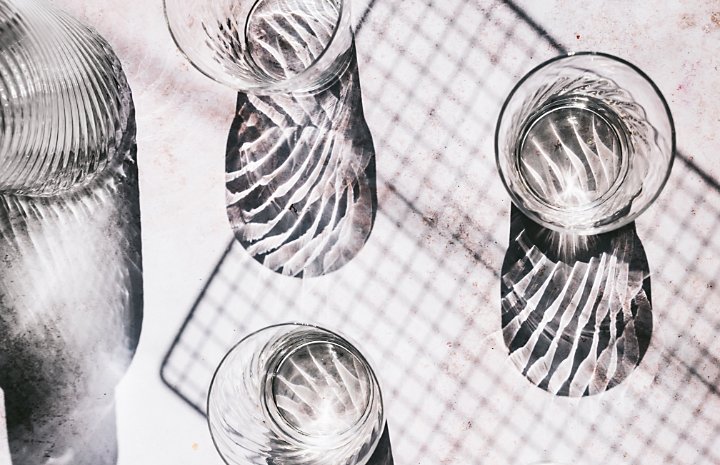 A flat lay photo of multiple drinking glasses next to a glass decanter