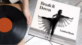 An image of someone placing a record on a record player. The album cover, which is also in frame, says "Break It Down" and features a multiple exposure image of a person doing ballet.