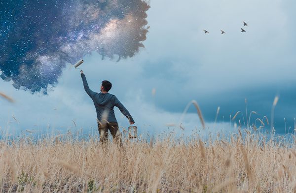 A digital painting of a person standing in a field painting the galaxy into the sky