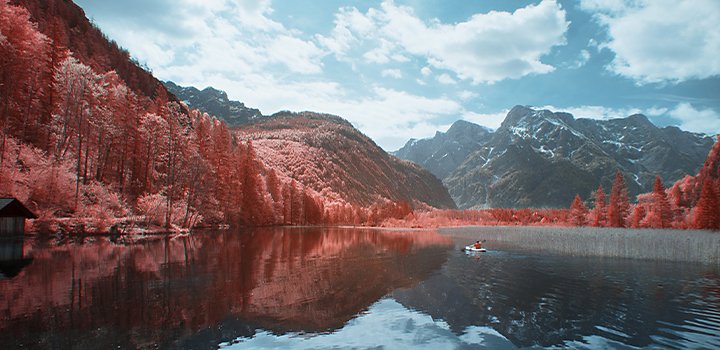 Infrared photo of a river running through a forest with mountains in the background