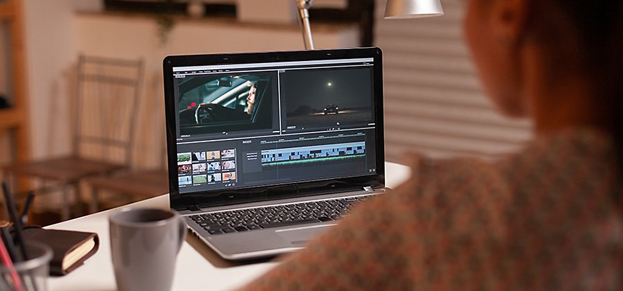 A person sitting at a desk creating a video trailer in Adobe Premiere Pro