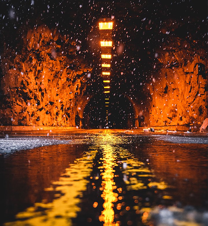 Water puddles and snow reflecting light from the lights of a car tunnel entrance