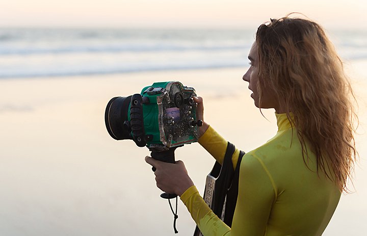 A photographer prepping their underwater camera at the beach
